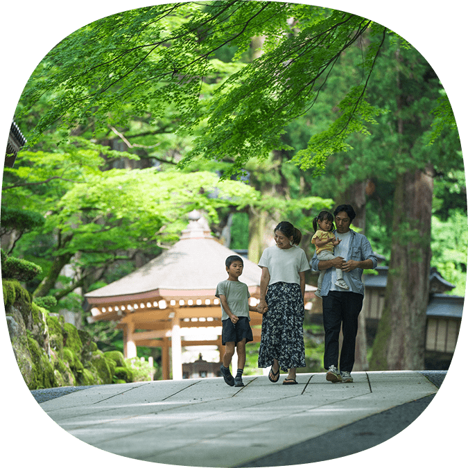 青もみじに包まれた参道を、手をつないで歩く家族連れ